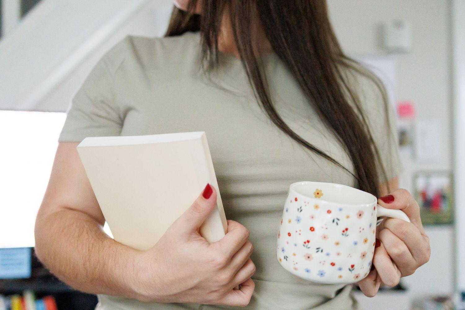 Person holding white ceramic mug with colorful polka dot pattern against light background.