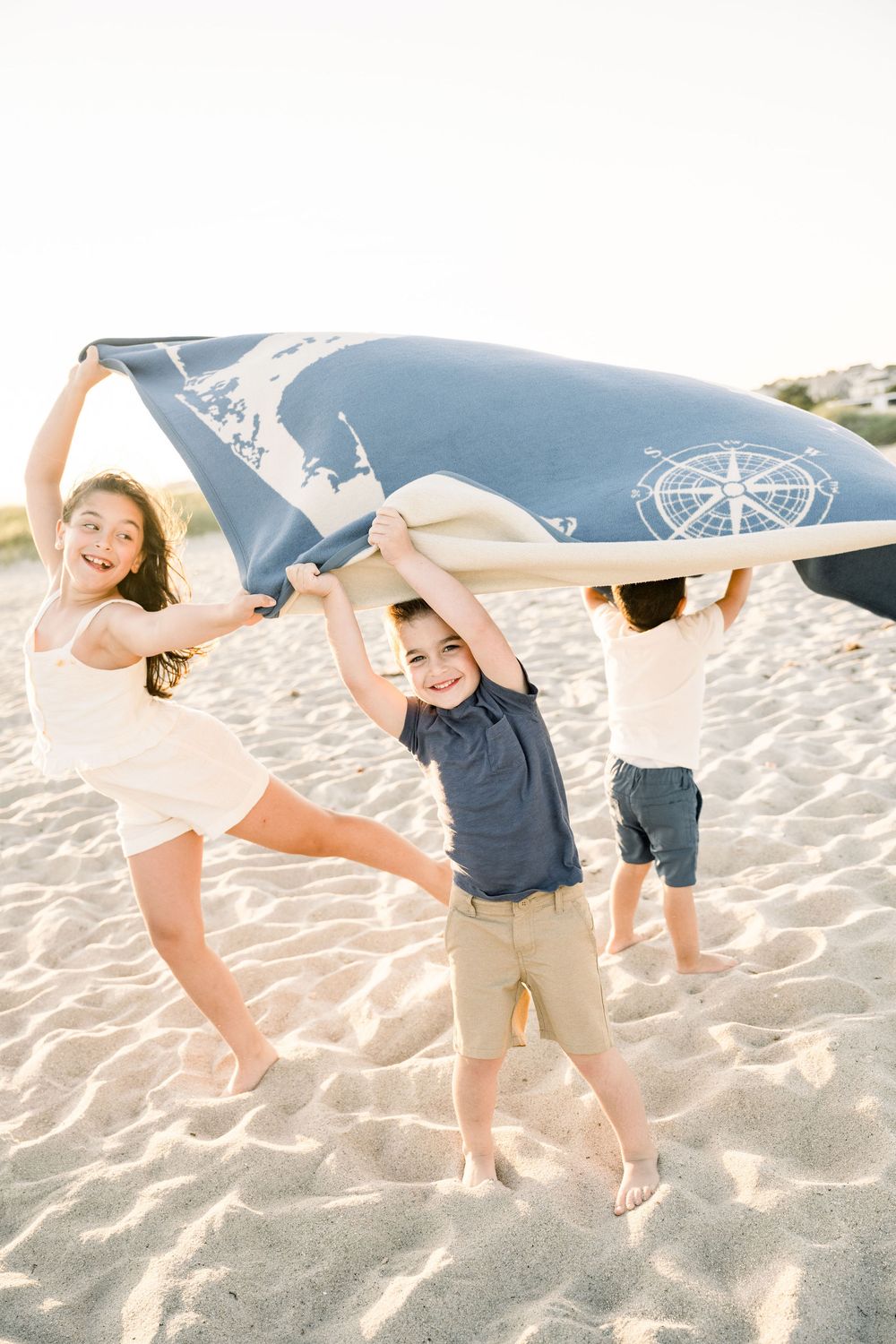 Playful couple dancing and twirling together on a sandy beach during a romantic photoshoot at sunset.