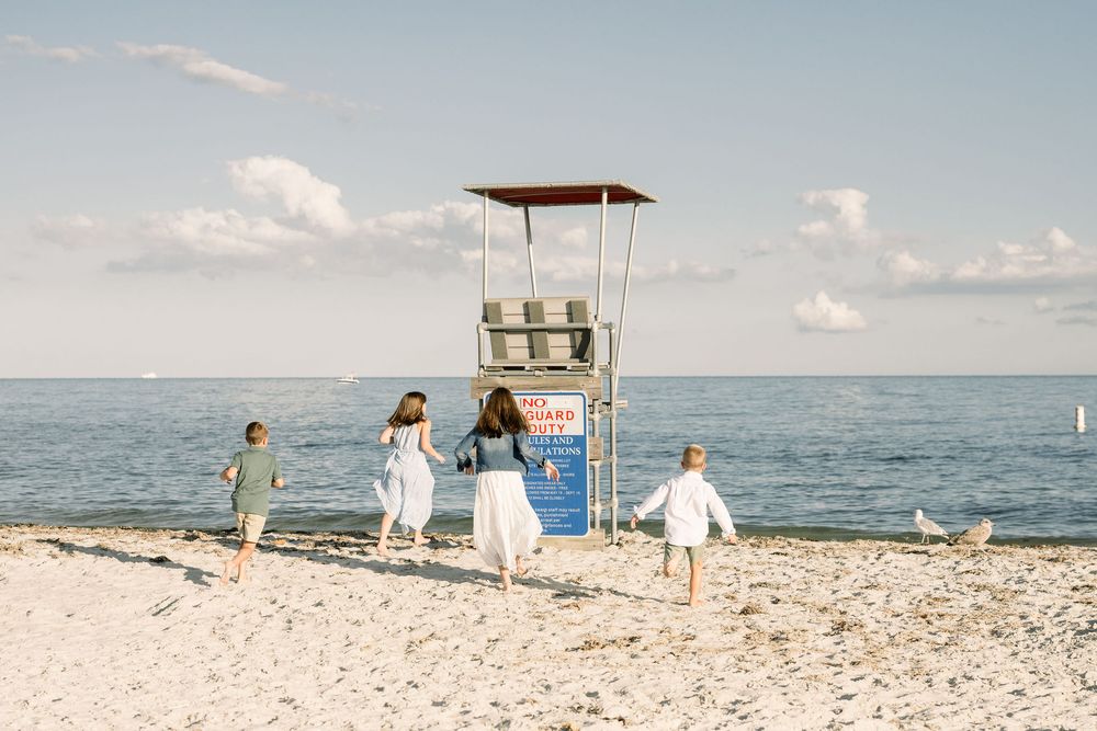 Panoramic sequence of a sunny beach wedding ceremony setup with white chairs and decorations along the shoreline.