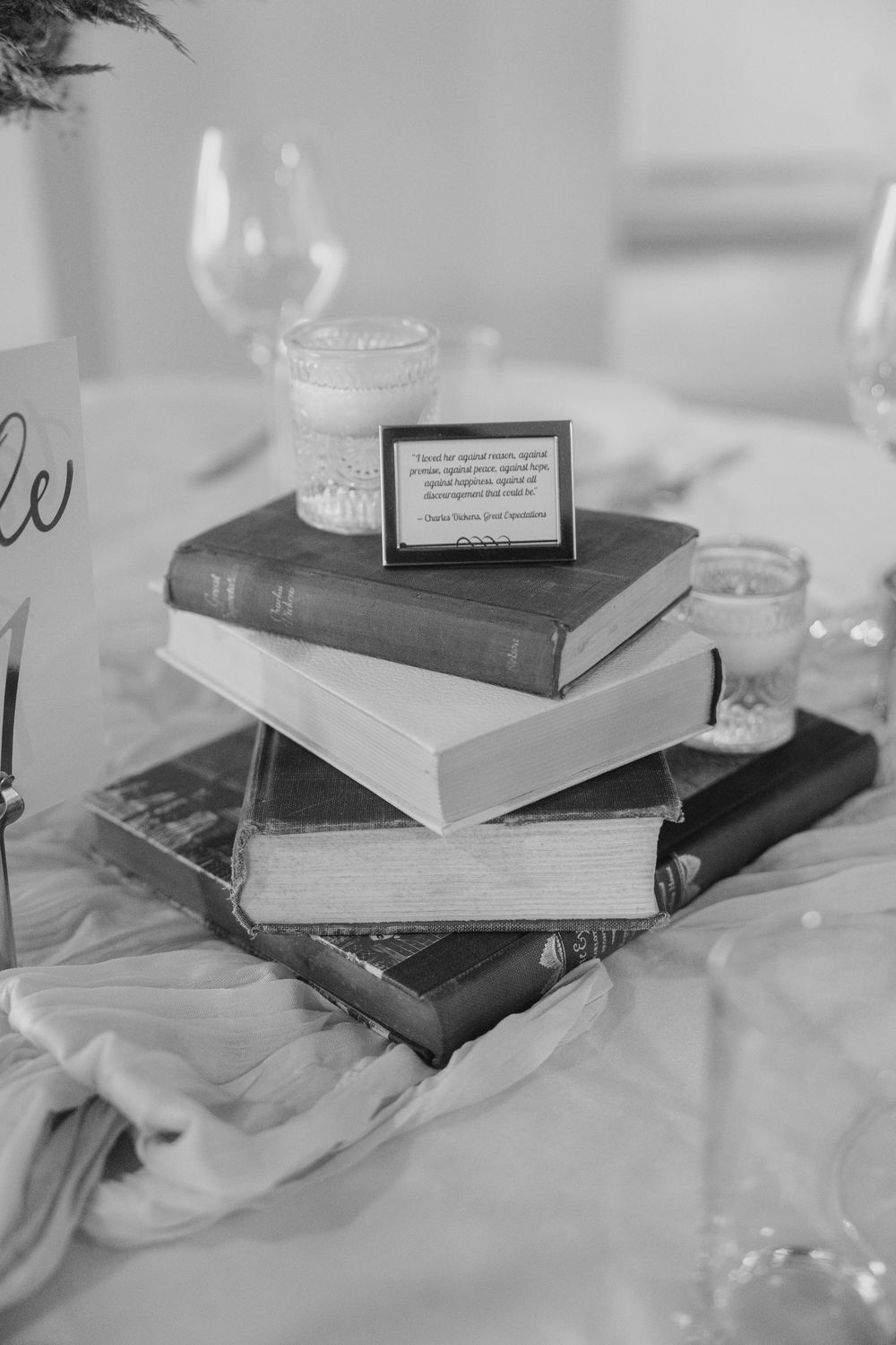 A collection of books stacked on a white surface in black and white photography.