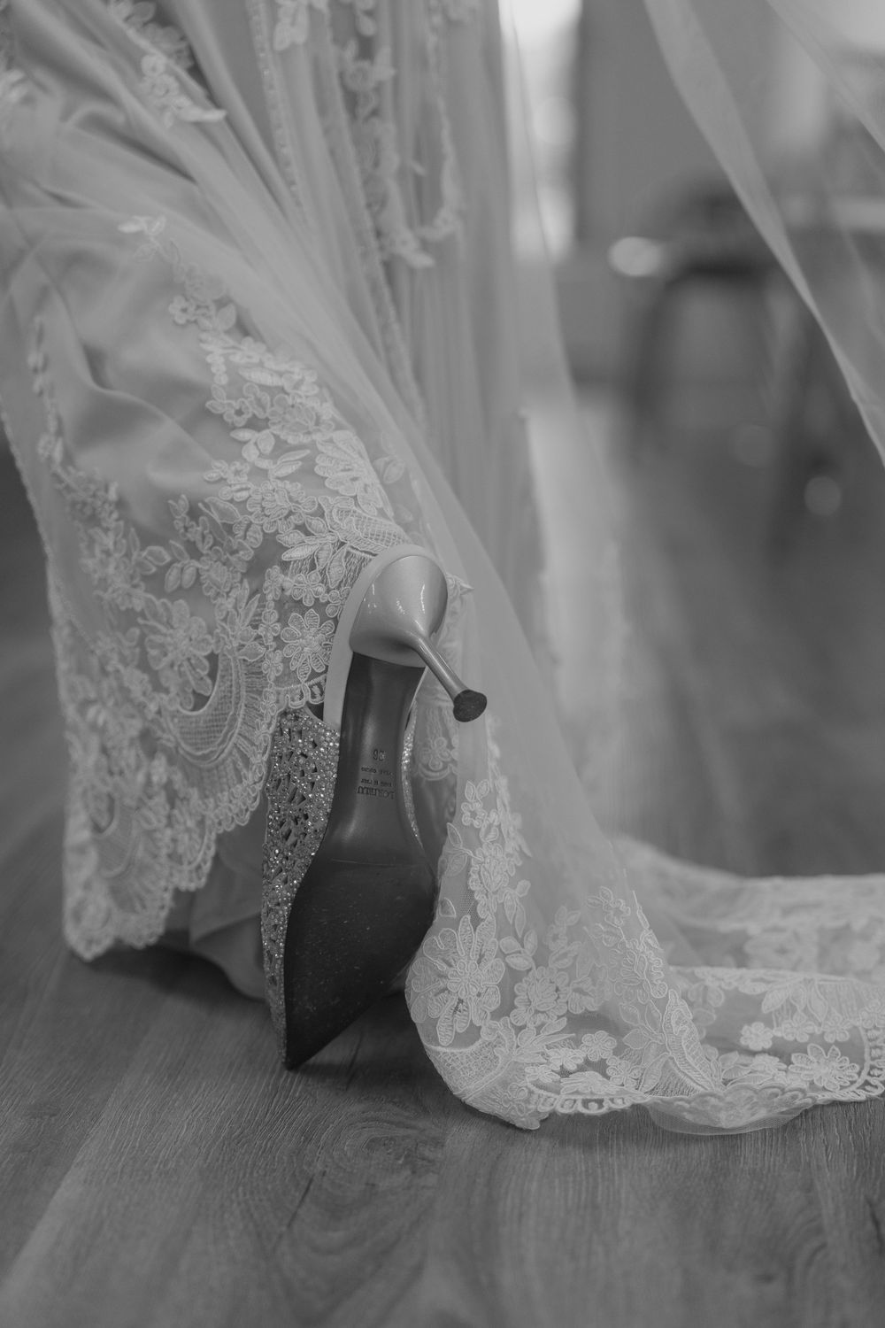 Close-up details of delicate lace trim on a wedding dress in black and white.