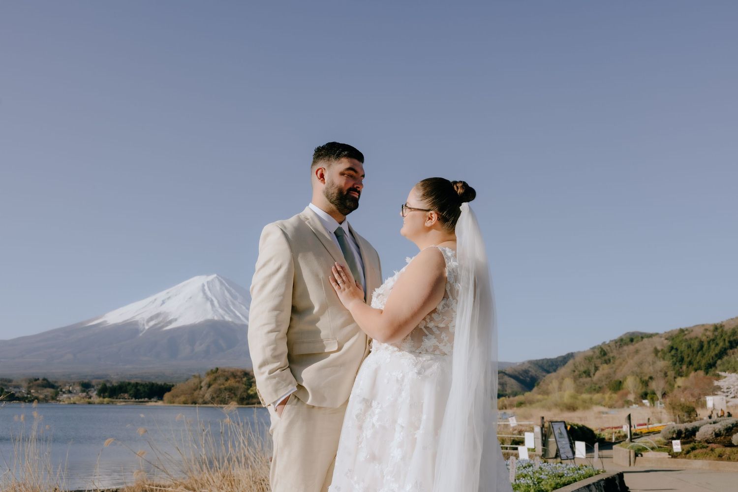 A couple shares an intimate moment during their wedding photoshoot with Mount Fuji in the background.