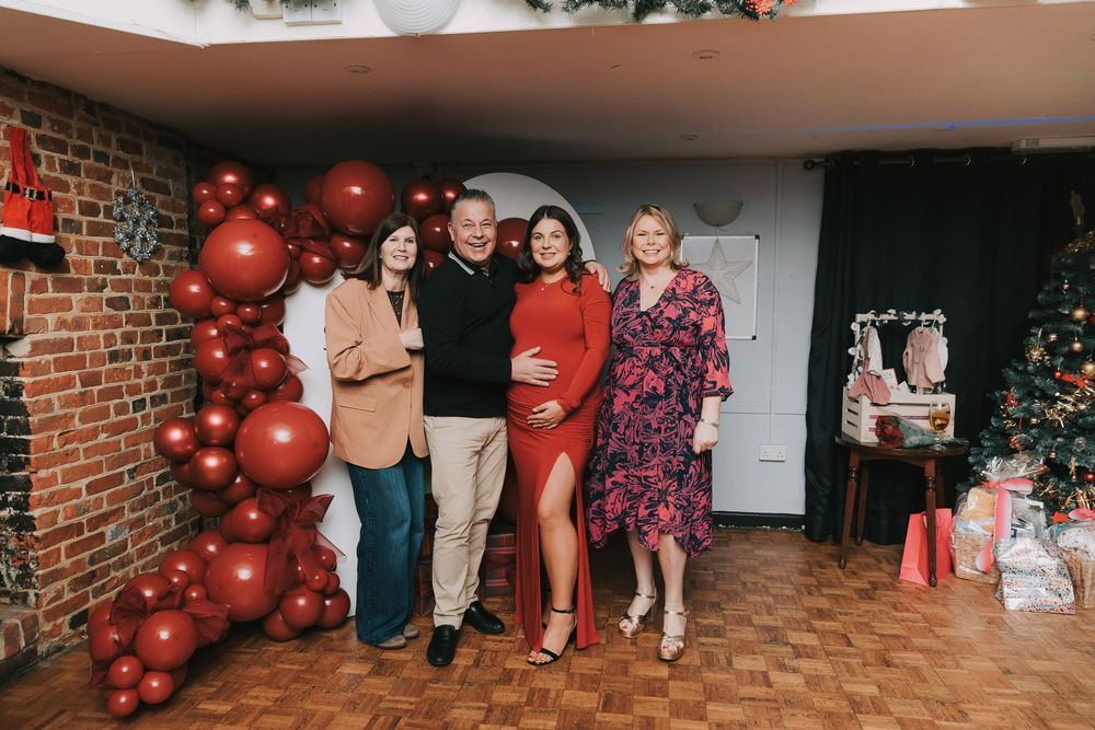 A baby shower party scene with red balloons decorating a brick wall interior space.