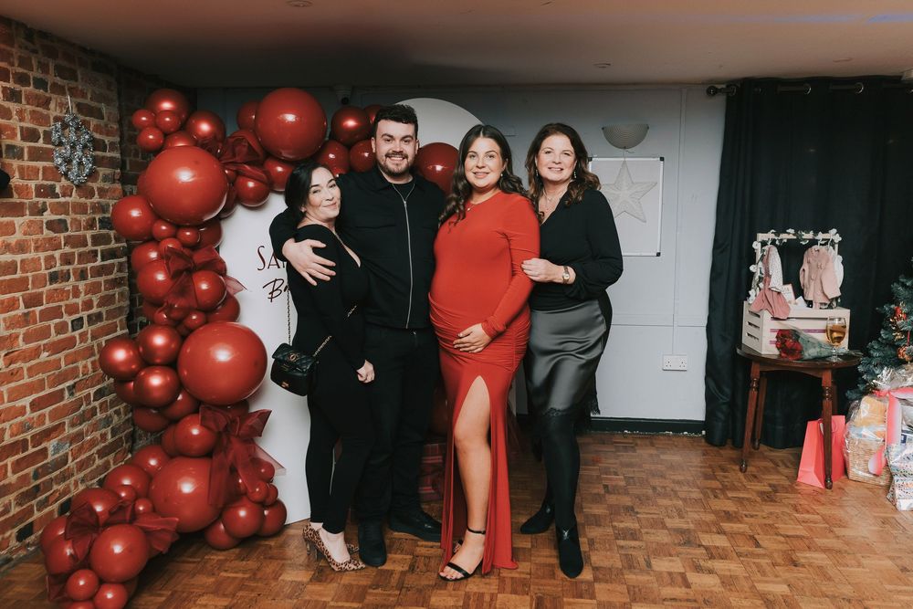 Holiday party scene with festive red balloon decorations against exposed brick walls.