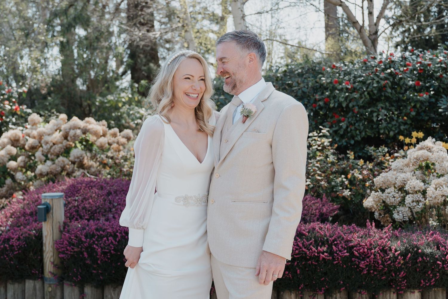 Romantic garden portrait with couple surrounded by flowering bushes.