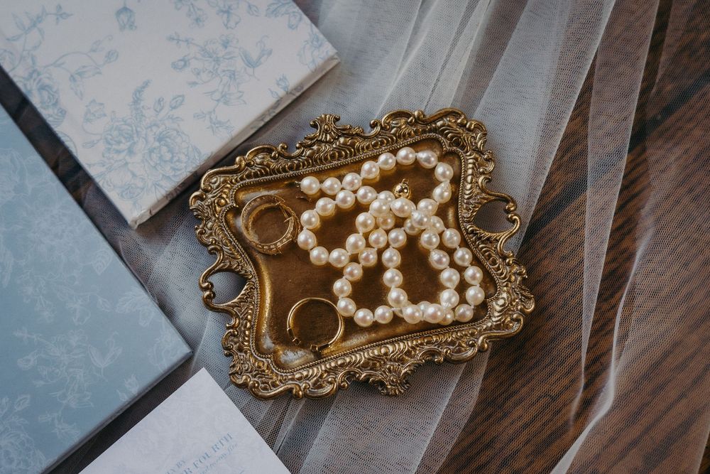 Vintage gold and pearl hair accessories and jewelry pieces arranged on blue surface.