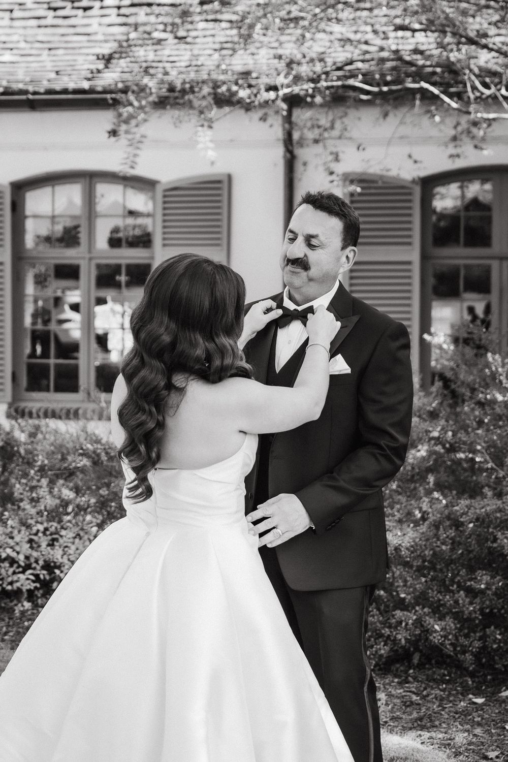 Romantic outdoor wedding portrait session in front of a white building with shutters.
