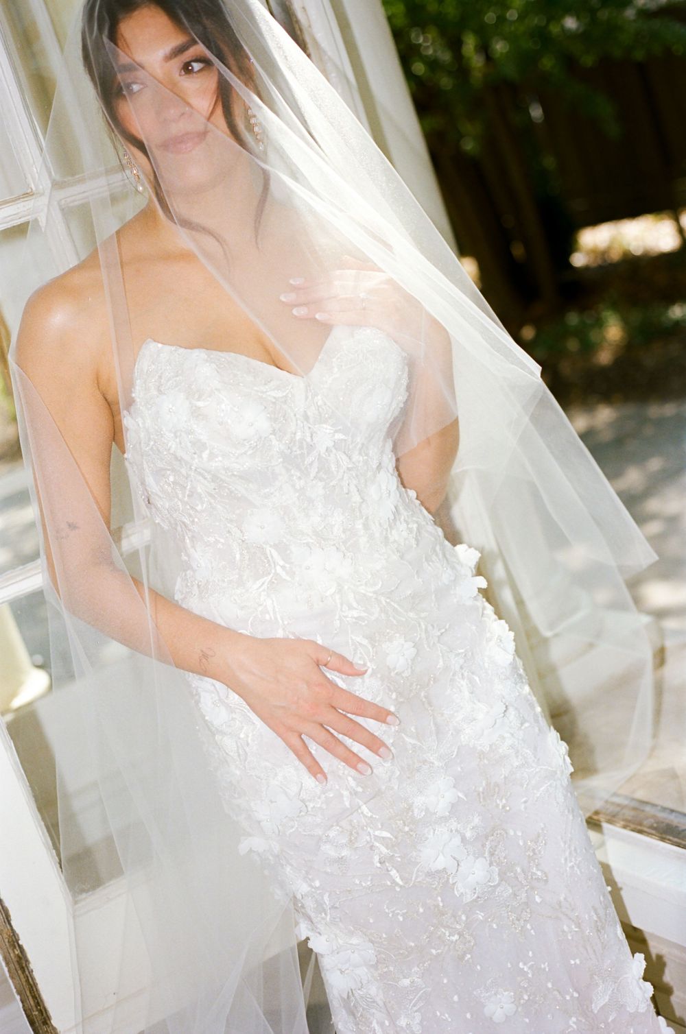 Close-up of intricate lace wedding dress details with flowing tulle veil.