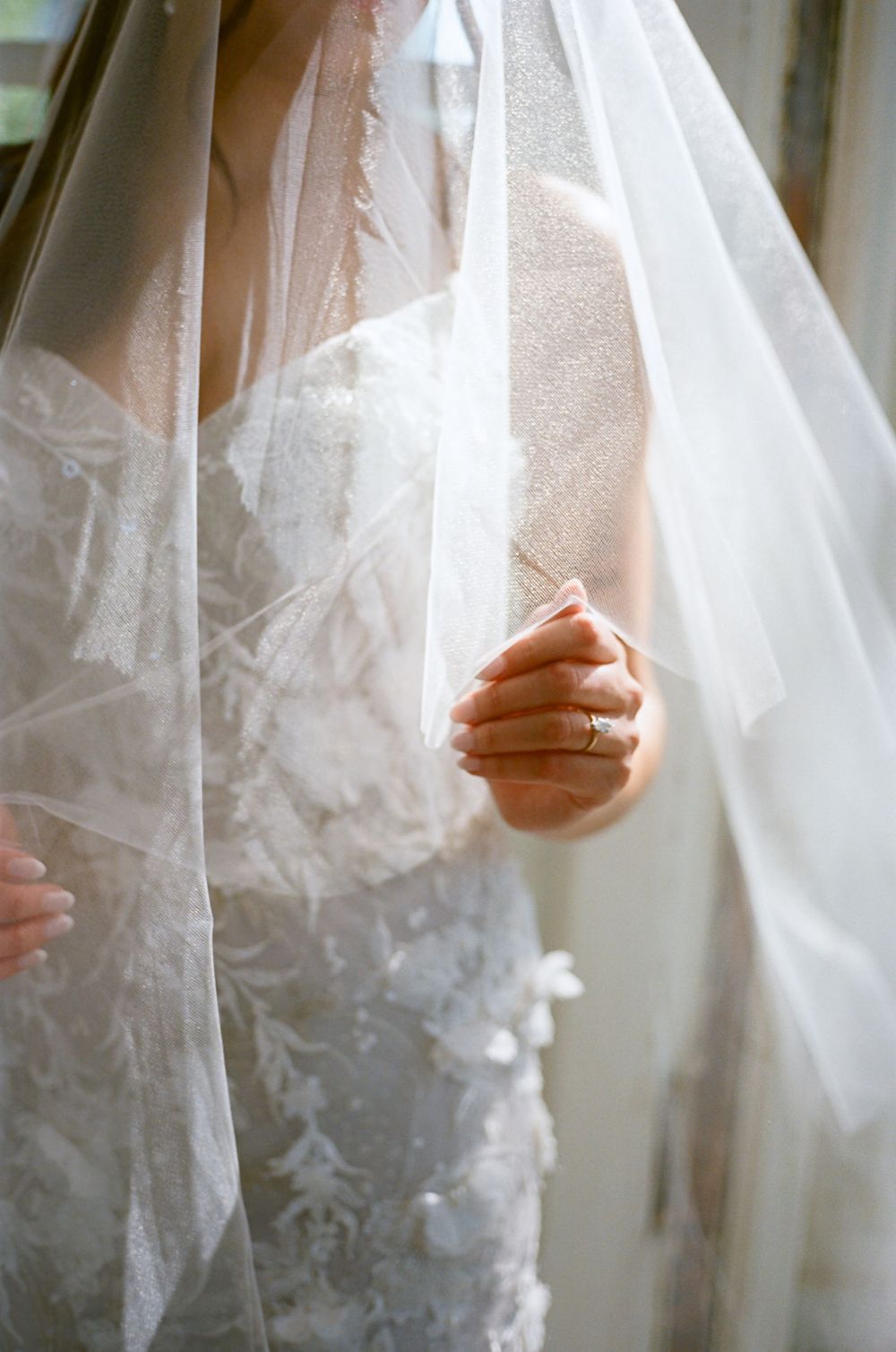 Delicate white tulle veil with lace details captured in soft window light.