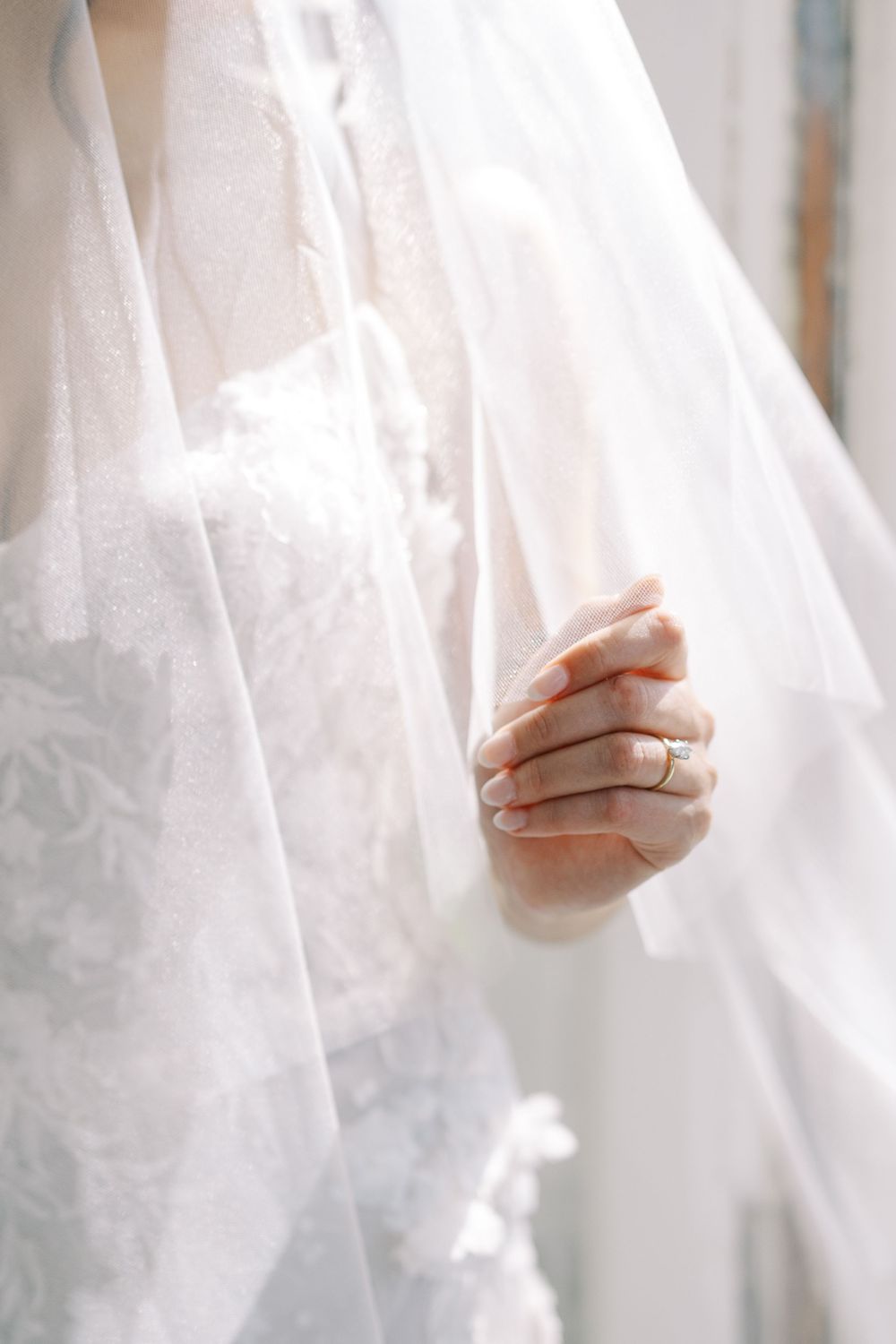 Close-up details of delicate white wedding dress lace and tulle fabric in natural light.