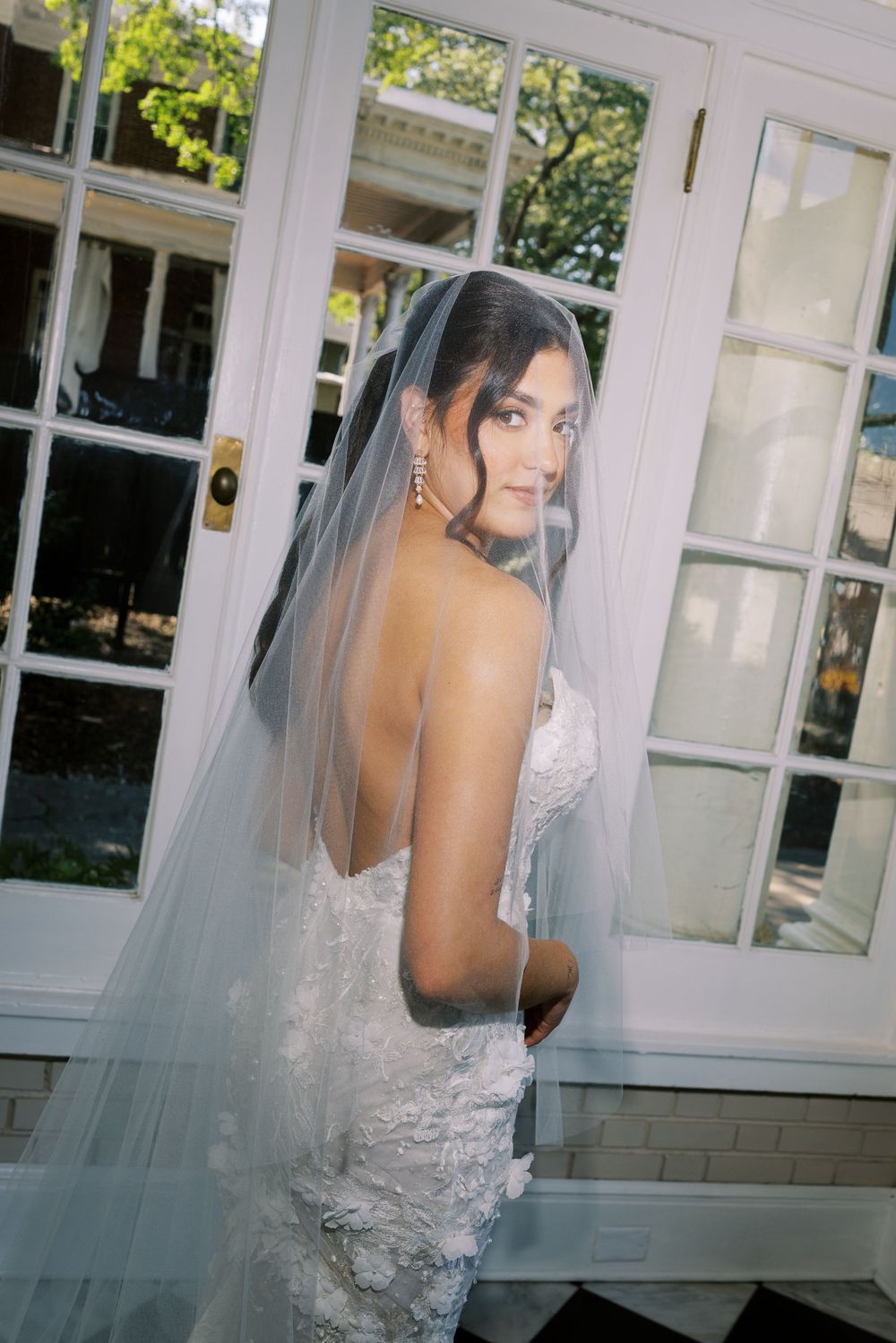 A series of bridal portraits showing a delicate lace wedding dress and flowing veil against white French doors.
