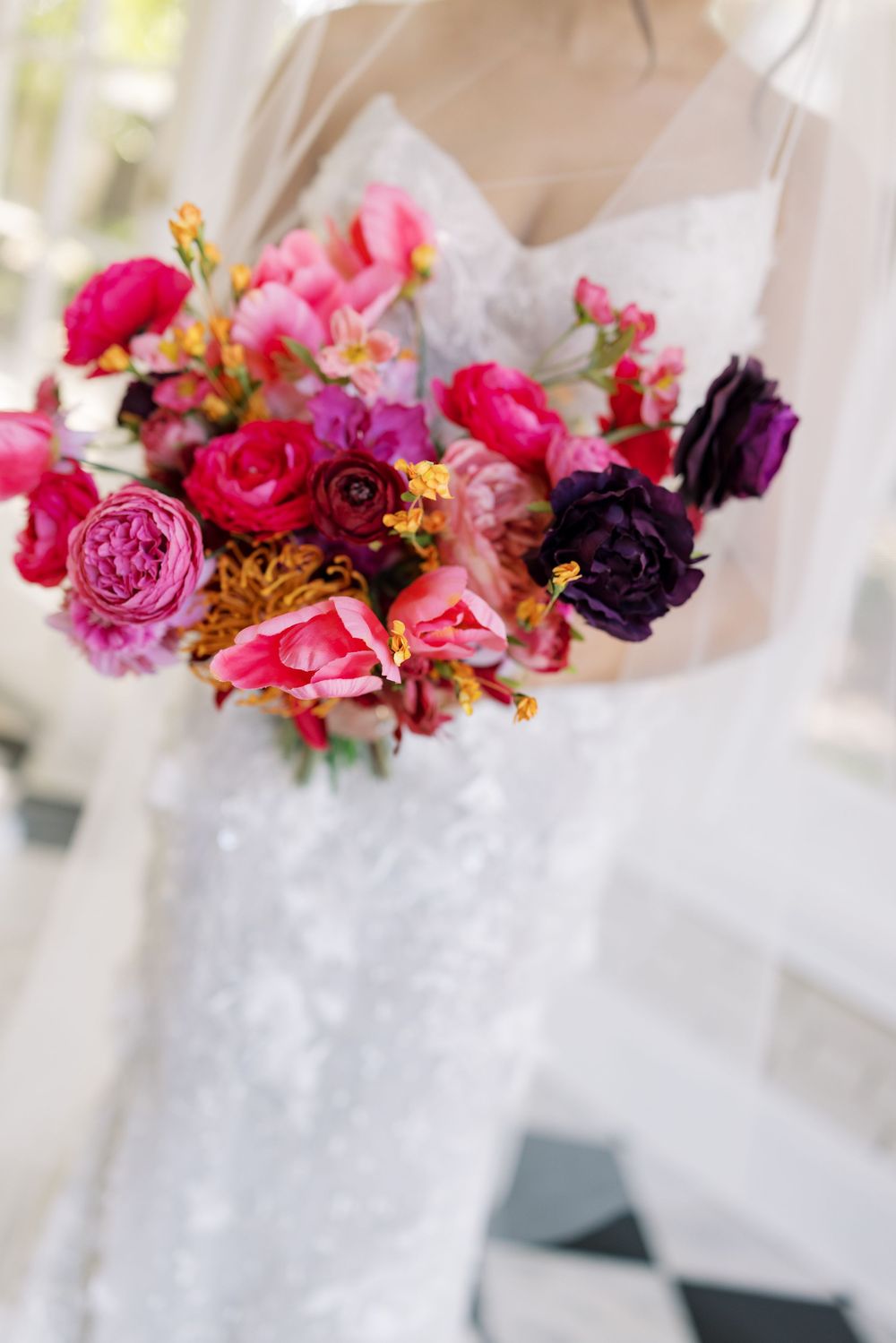 Vibrant pink and purple floral arrangements with roses and seasonal blooms in white vases.