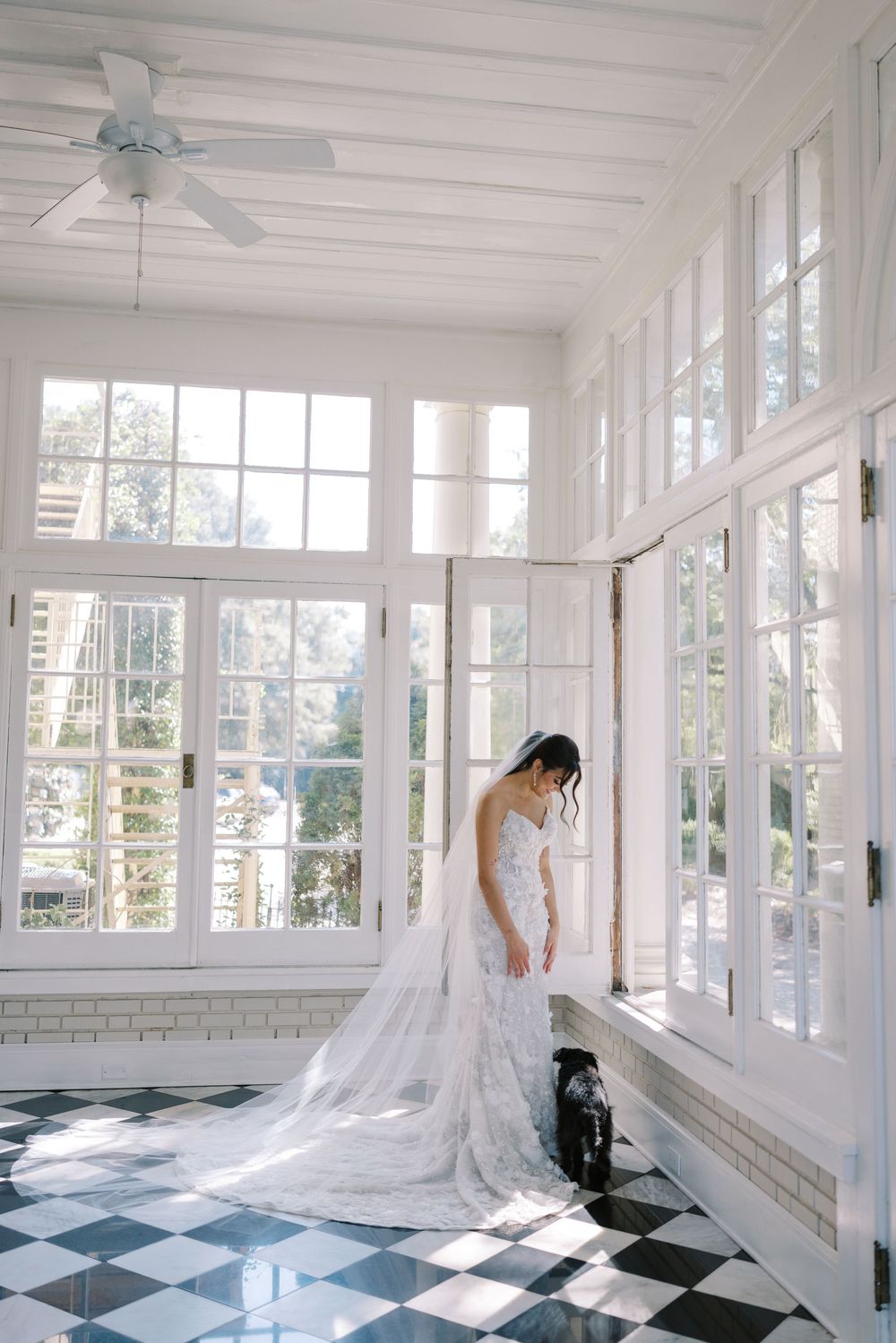 Sunlit bridal portrait in white room with checkered floor and floor-to-ceiling windows.