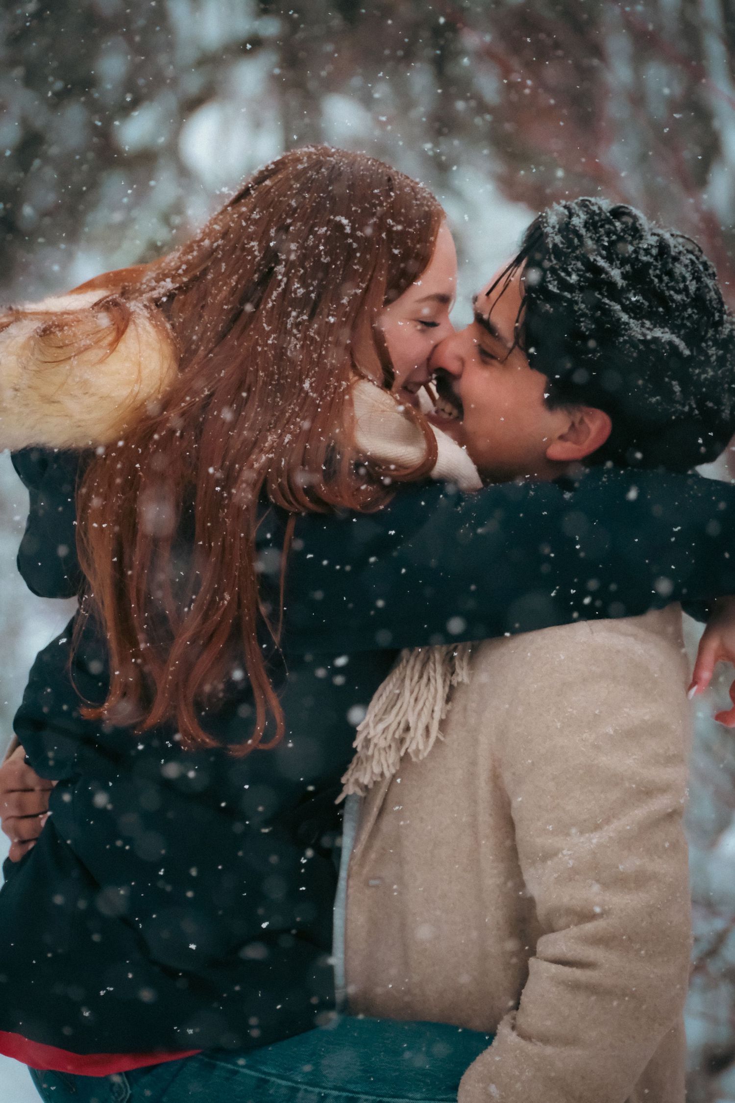 Romantic winter scene with falling snow as couple shares intimate moment in beige sweaters.