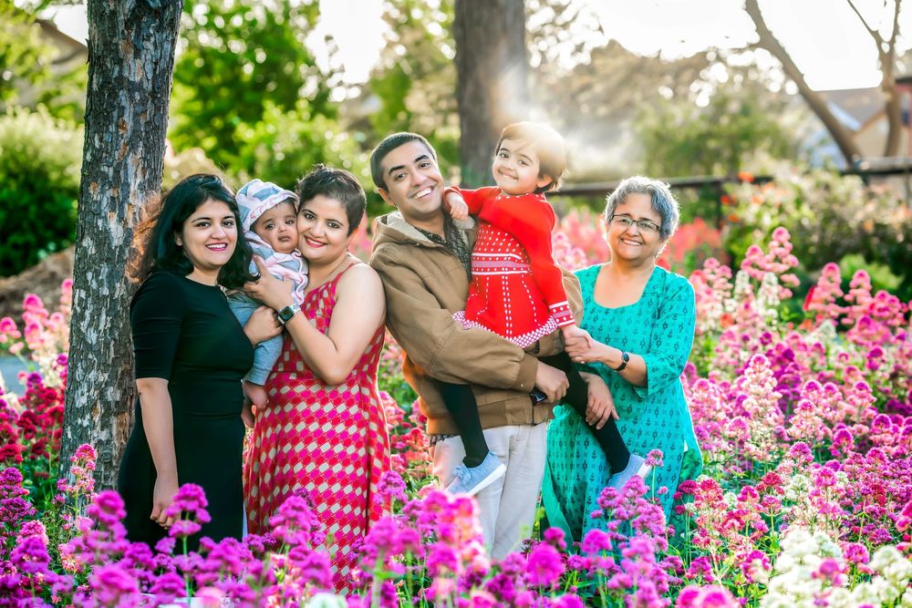 A group stands together in a vibrant garden filled with pink flowers and blooming trees on a sunny day.