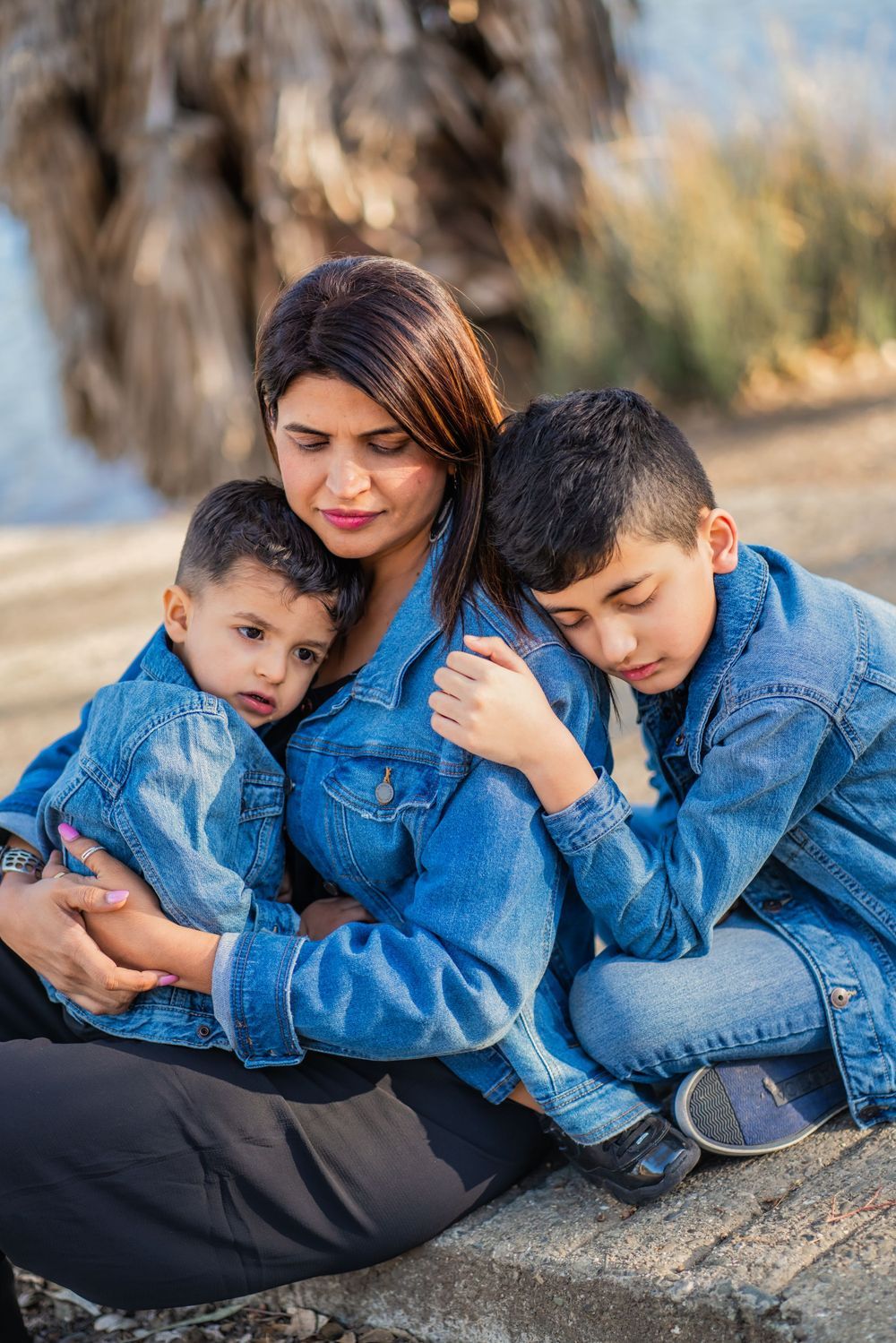 A series of artistic portraits showing two people in denim jackets resting together on a rocky surface at sunset.
