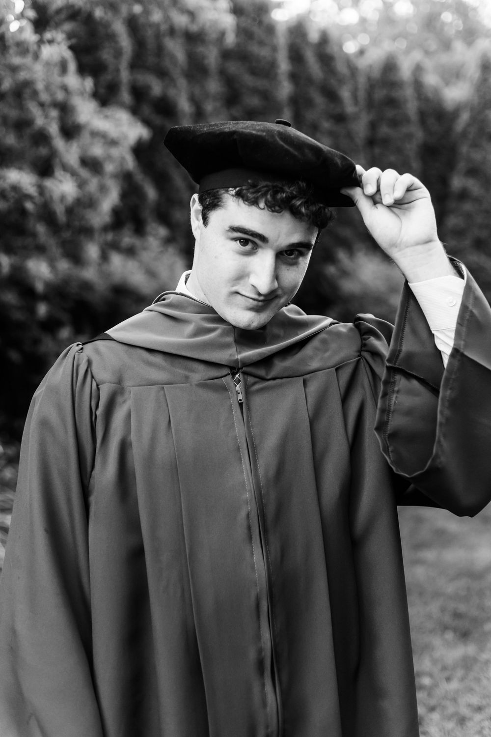 Black and white photo showing graduation cap and gown details in an outdoor setting.