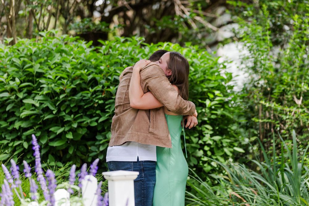 A special moment unfolds between two people in a verdant garden setting surrounded by greenery.