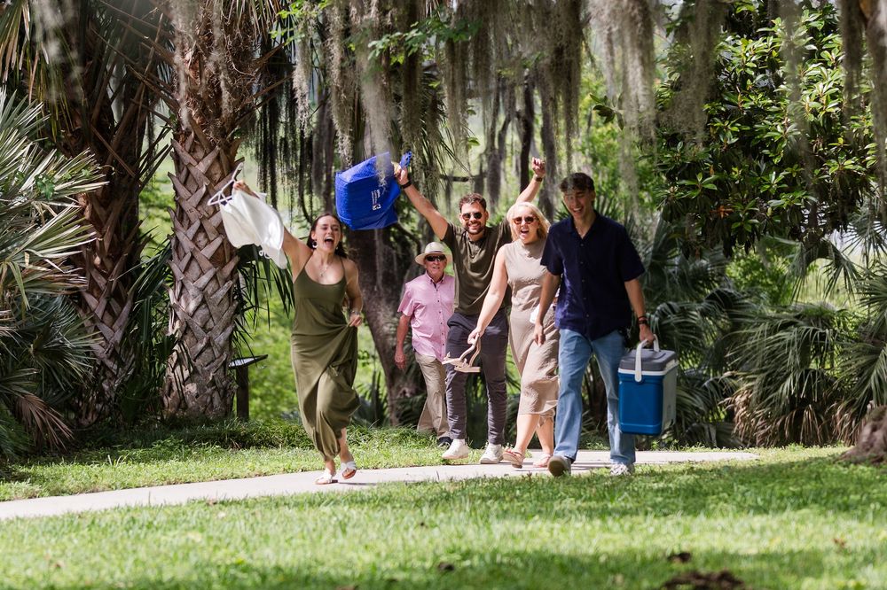A celebration scene with onlookers in a garden path lined with Spanish moss draped trees.