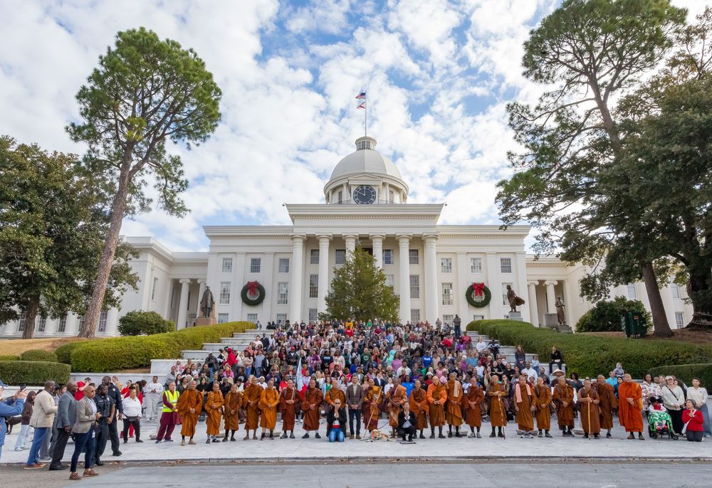 A panoramic view of the Virginia State Capitol building with holiday wreaths and a large crowd gathered outside.