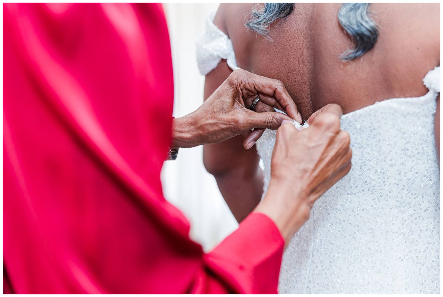Close up shot of hands adjusting a white dress detail during a formal preparation.