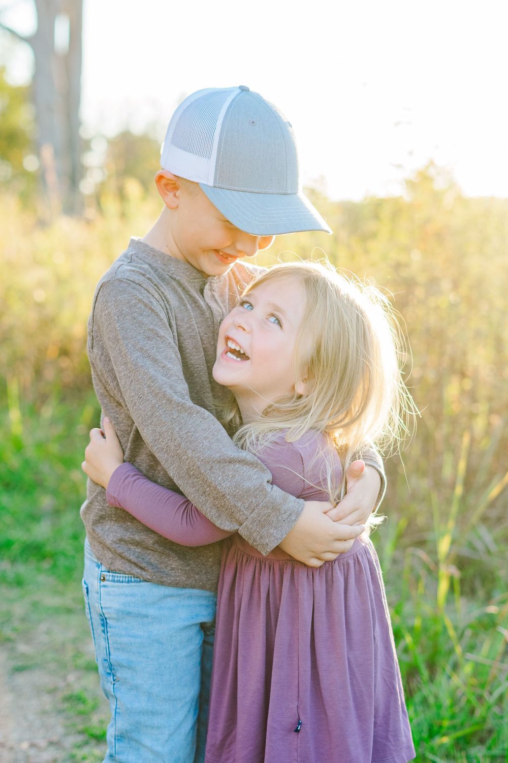 brother and sister hugging and laughing during golden hour