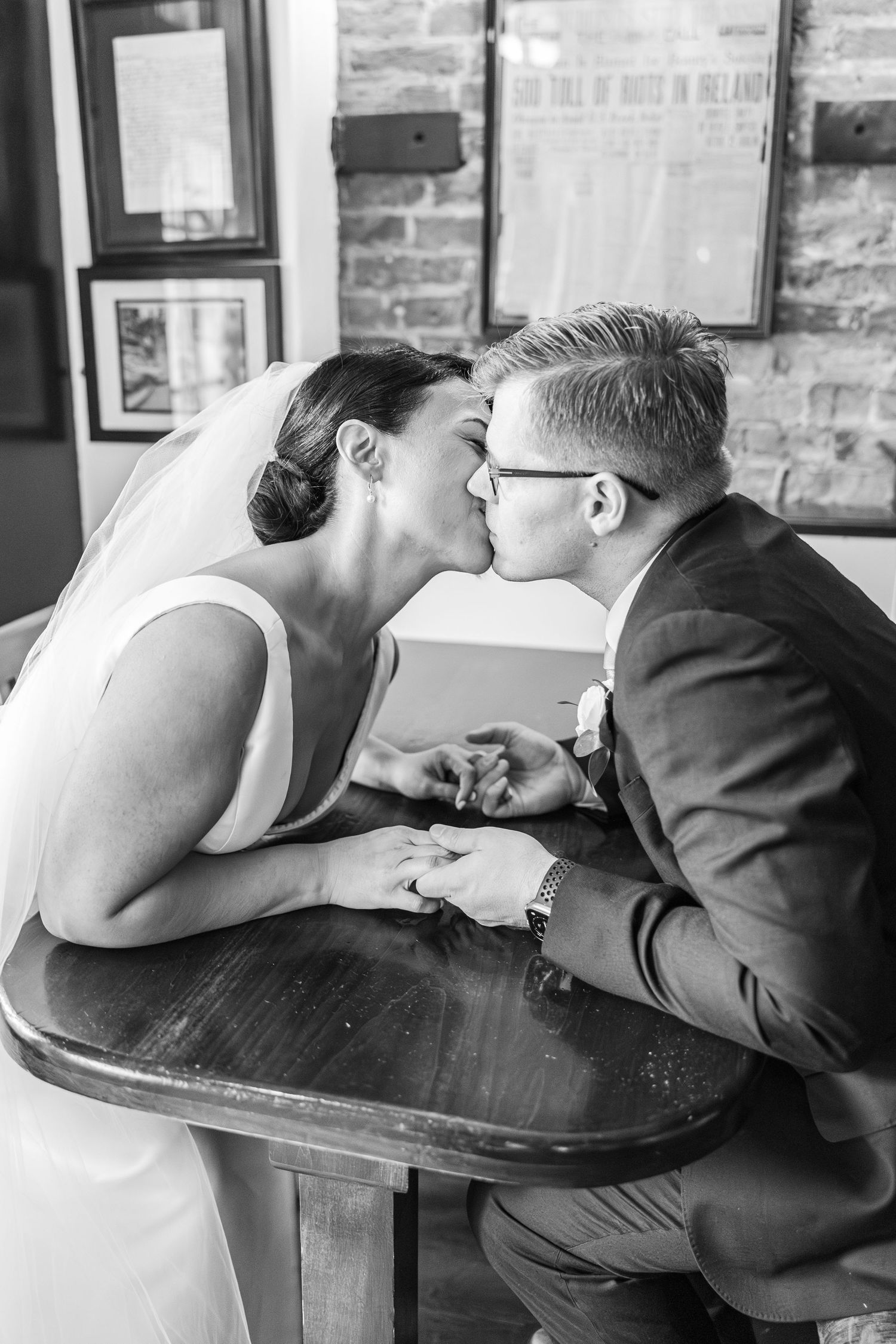 Three sequential black and white photos show a couple in wedding attire sharing romantic kisses.