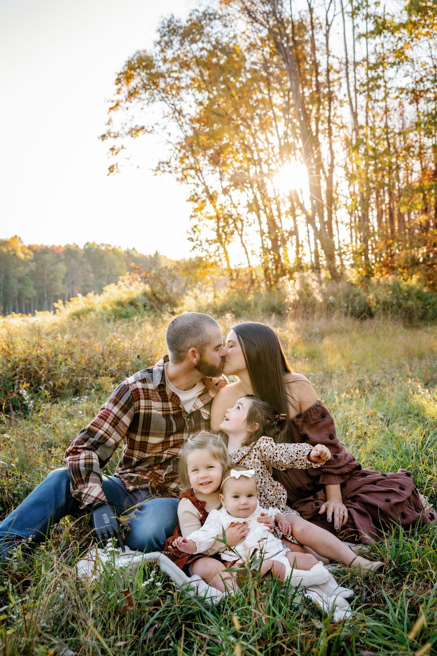 Family lying together on grass during golden hour autumn photoshoot.