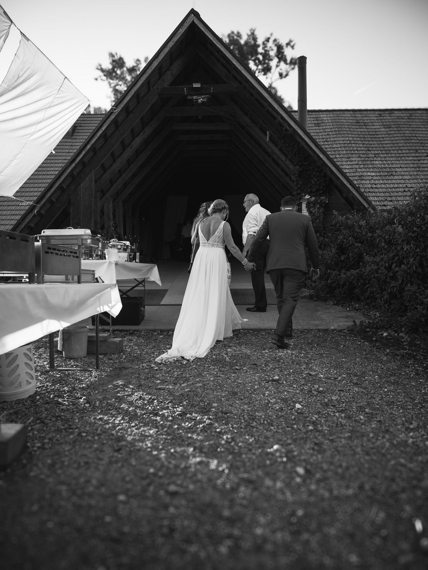 Black and white wedding photos showing couple walking near a rustic building.