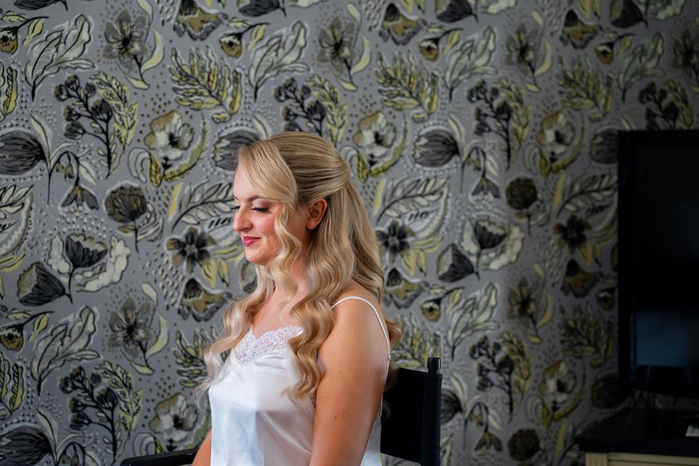 A person in a white top poses against a floral wallpaper background in a series of four connected photos.