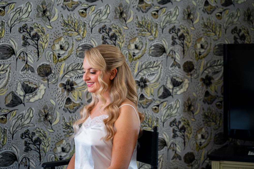 Woman in white sleeveless top poses against floral wallpaper background in three similar shots.