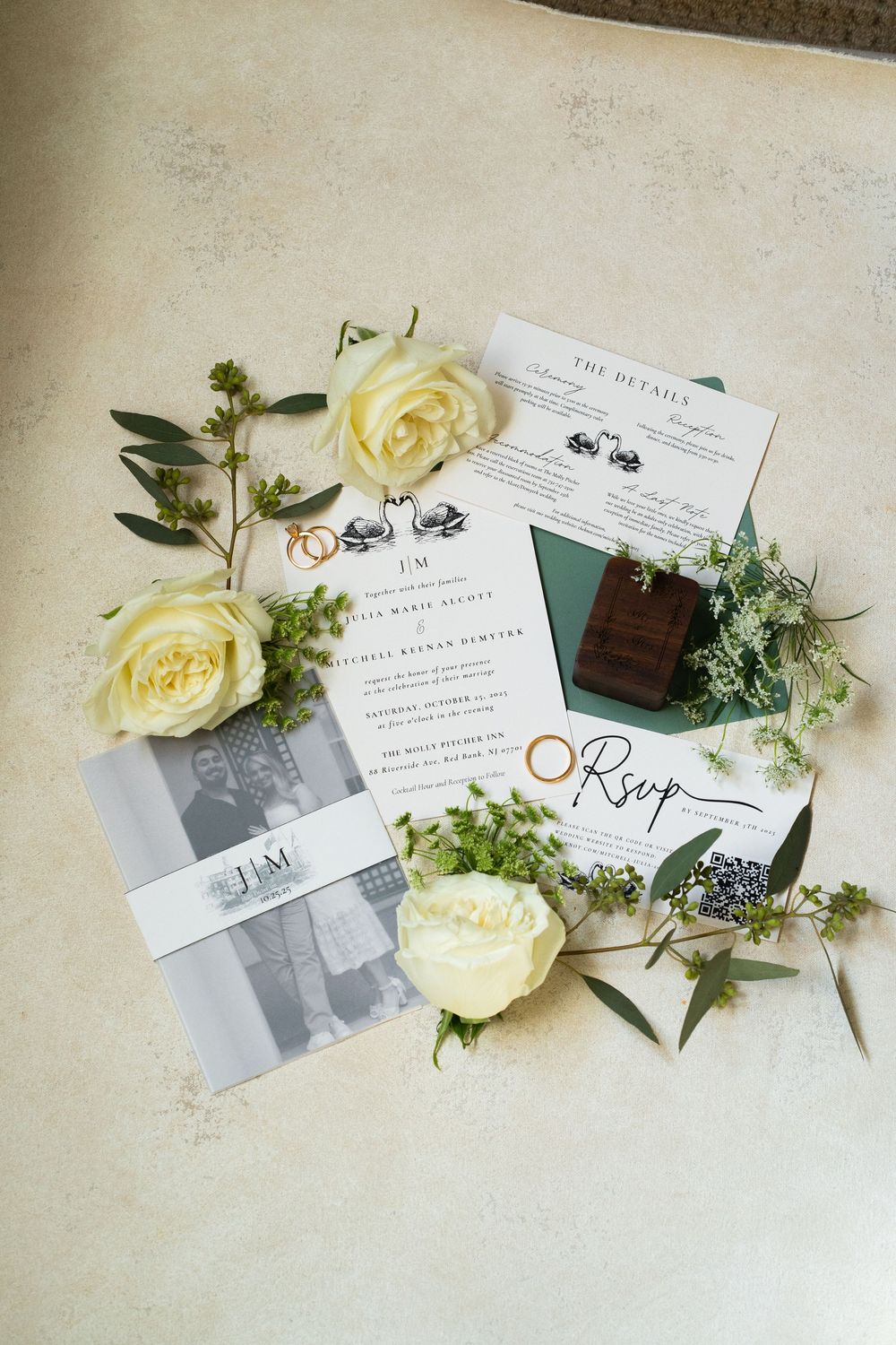Wedding invitation suite with white roses and greenery arranged on a light beige background in a minimalist style.