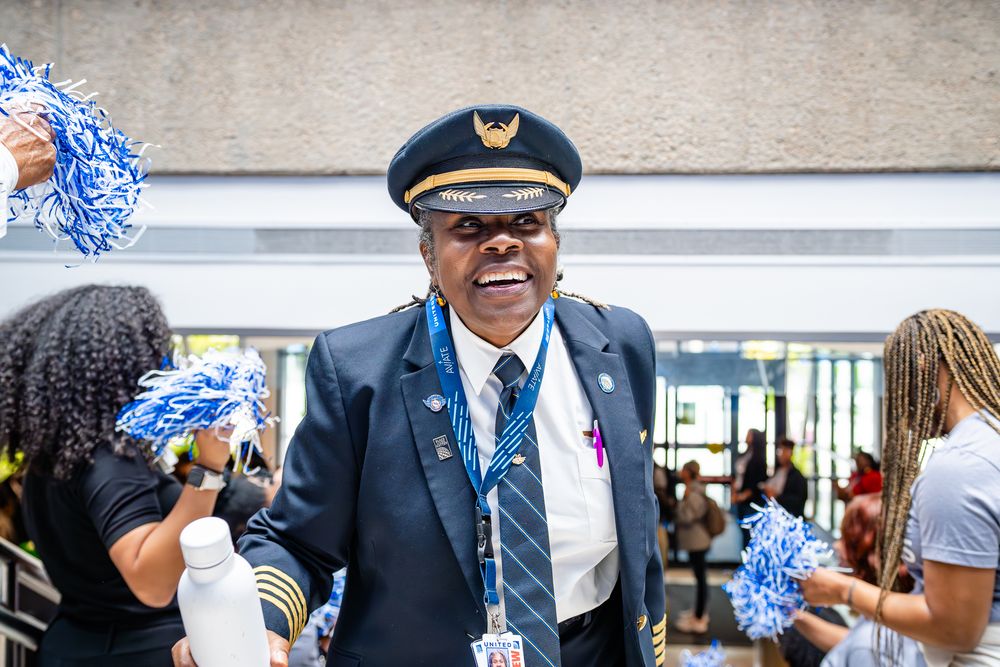 Airline crew members in uniforms greeting attendees at a professional event.