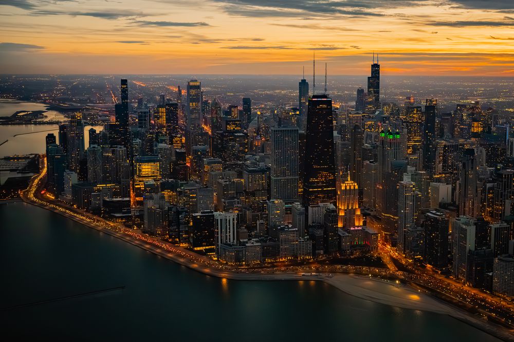 Panoramic Chicago skyline at sunset with orange and purple sky over downtown buildings.