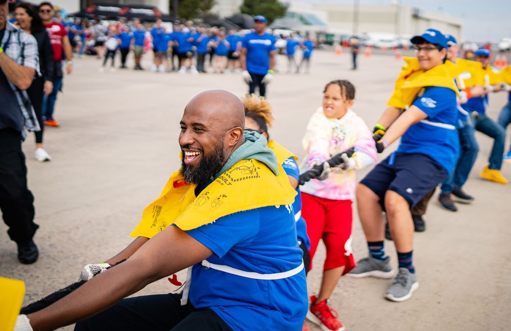 Crowd of people in blue and yellow uniforms walking together at an outdoor event.