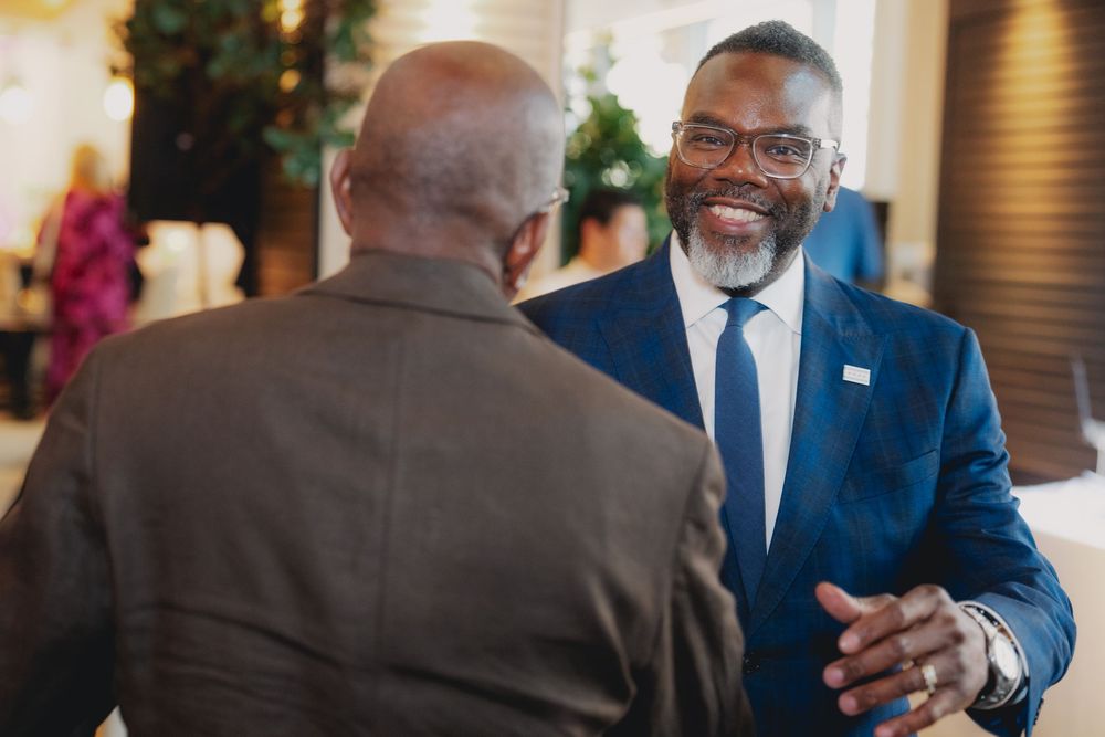 Two professional men in suits engaged in a friendly conversation at a formal networking event.