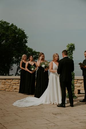 Wedding ceremony in progress on stone patio with wedding party in black and white attire.