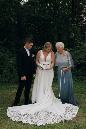 Final adjustments being made to an elegant white wedding dress with elaborate lace train.