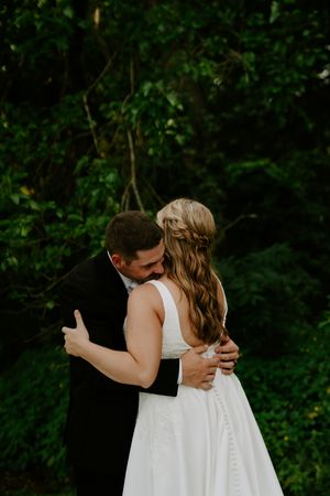 A romantic outdoor wedding portrait showing a tender embrace between newlyweds.