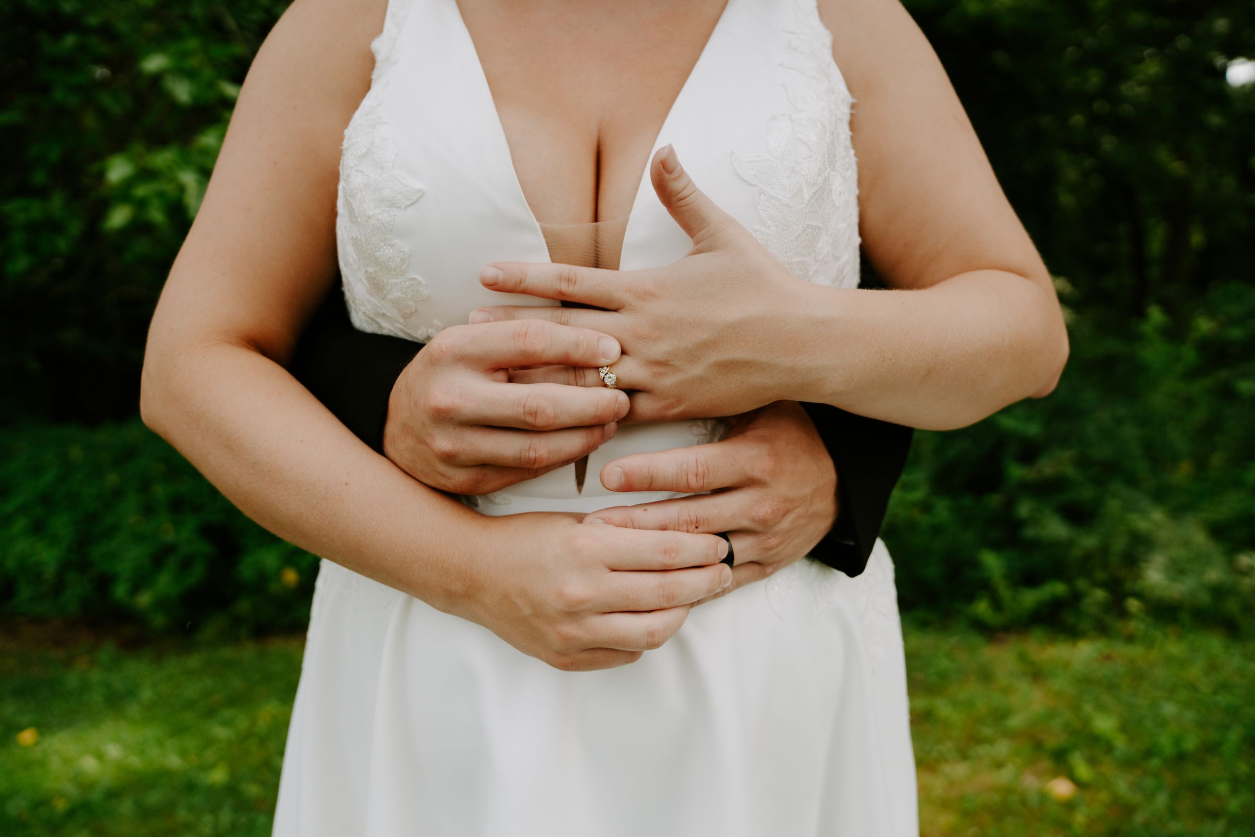 Close-up detail of a white lace wedding dress against natural lighting.
