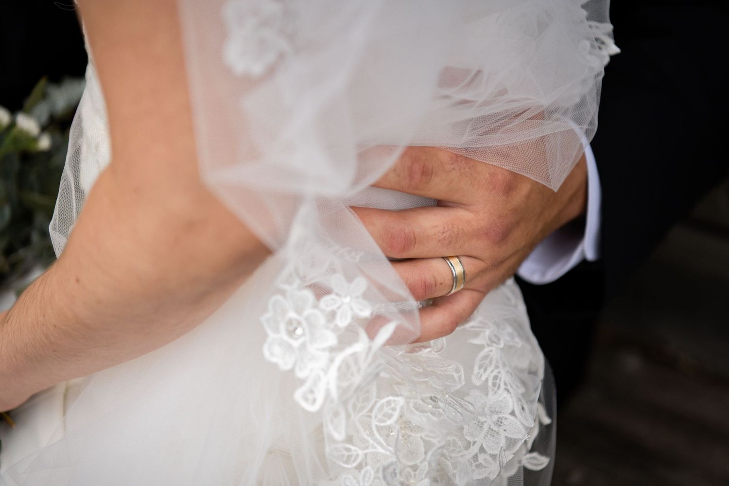 A close-up detail shot of delicate white lace fabric embellishments on a wedding dress.