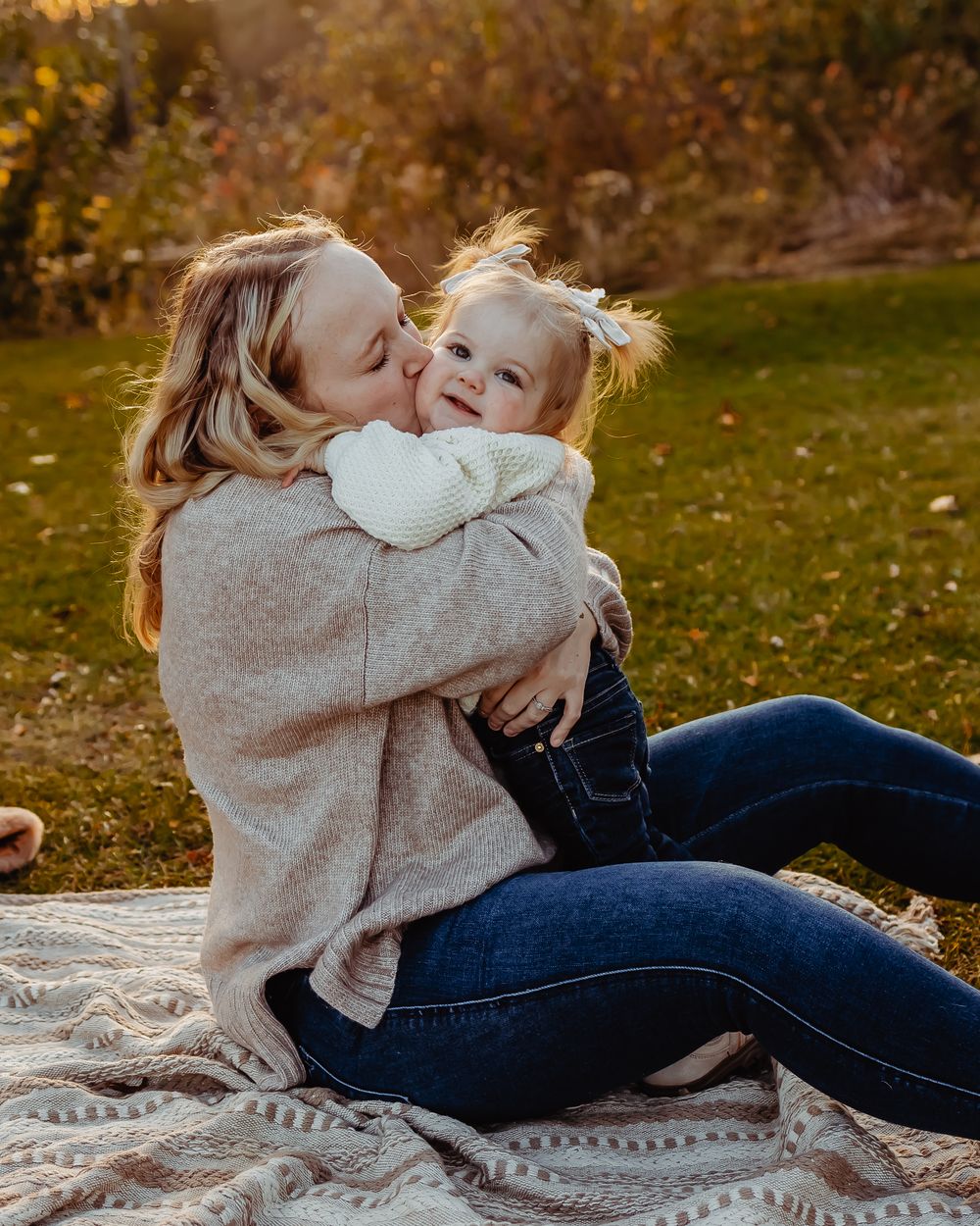 A heartwarming moment captured between parent and child sitting on a blanket during golden hour outdoors.