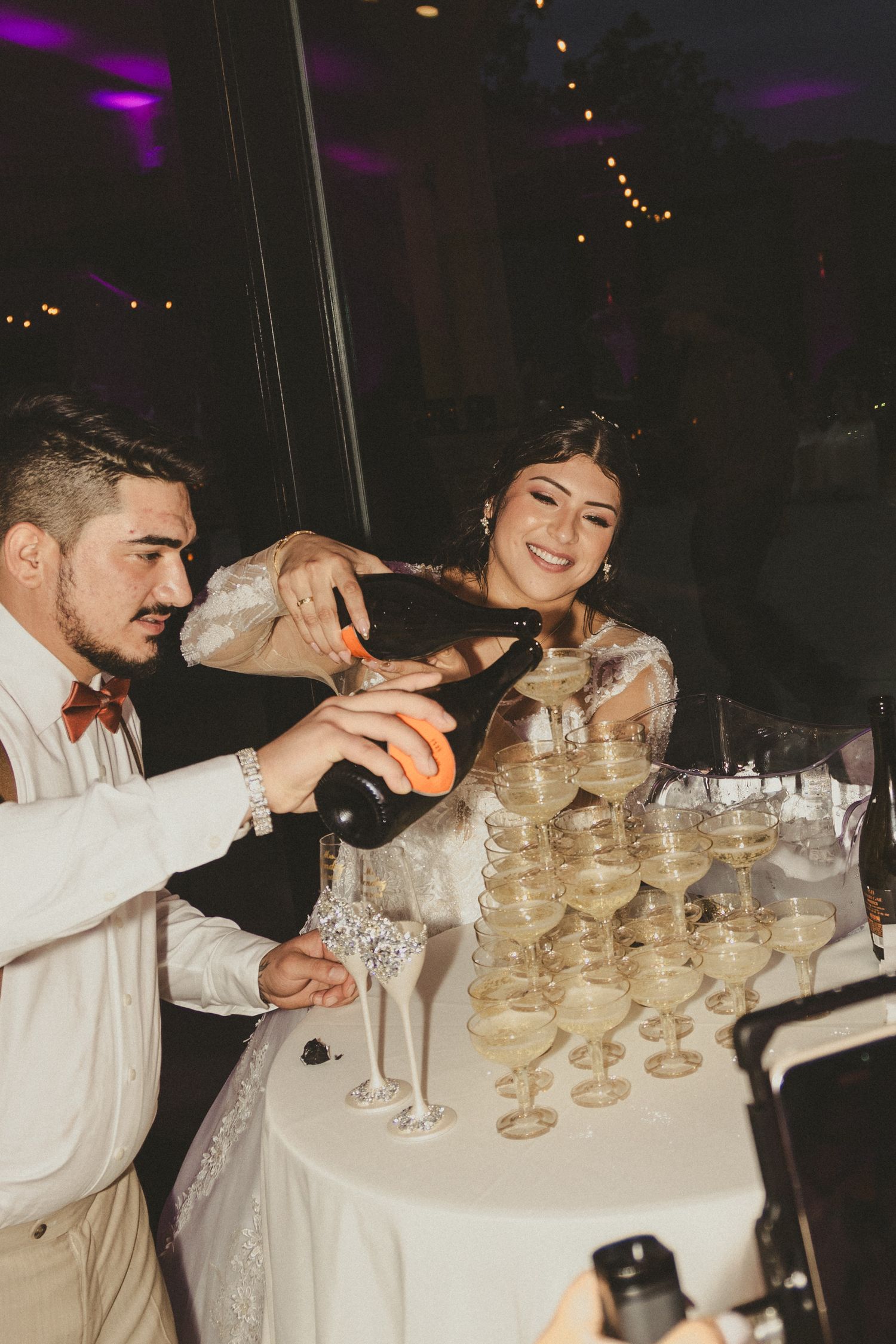 Champagne being poured into a pyramid of elegant glasses at an evening celebration.