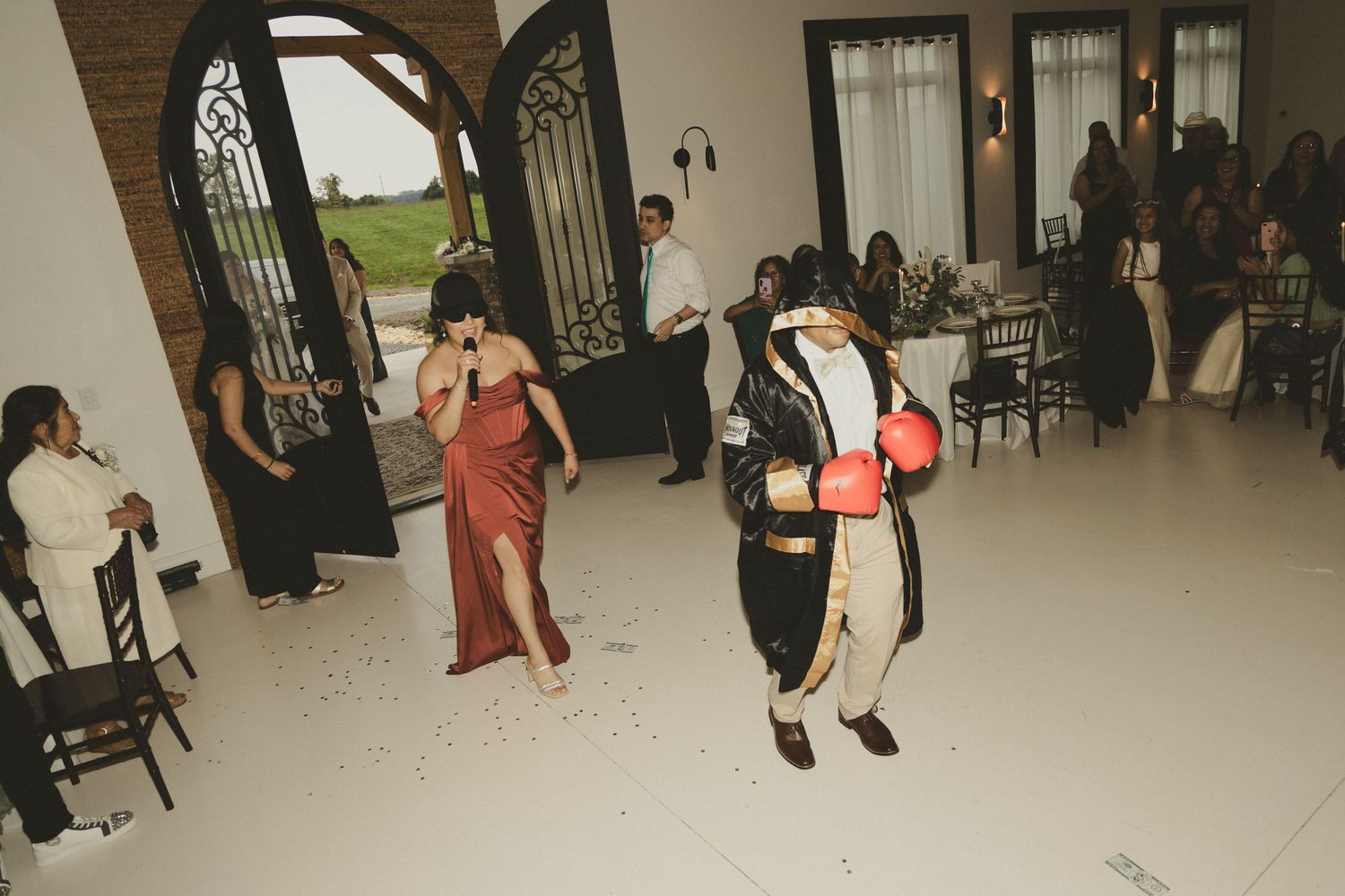 People in formal attire dancing and socializing at an elegant indoor venue with arched doorways and white floors.