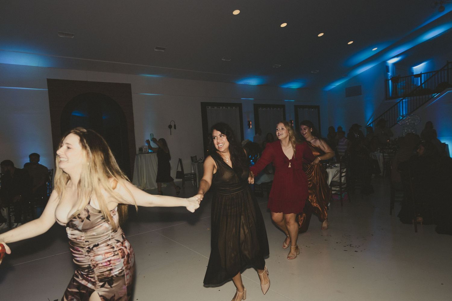 Dancers move expressively in a dimly lit dance studio space with blue lighting effects.