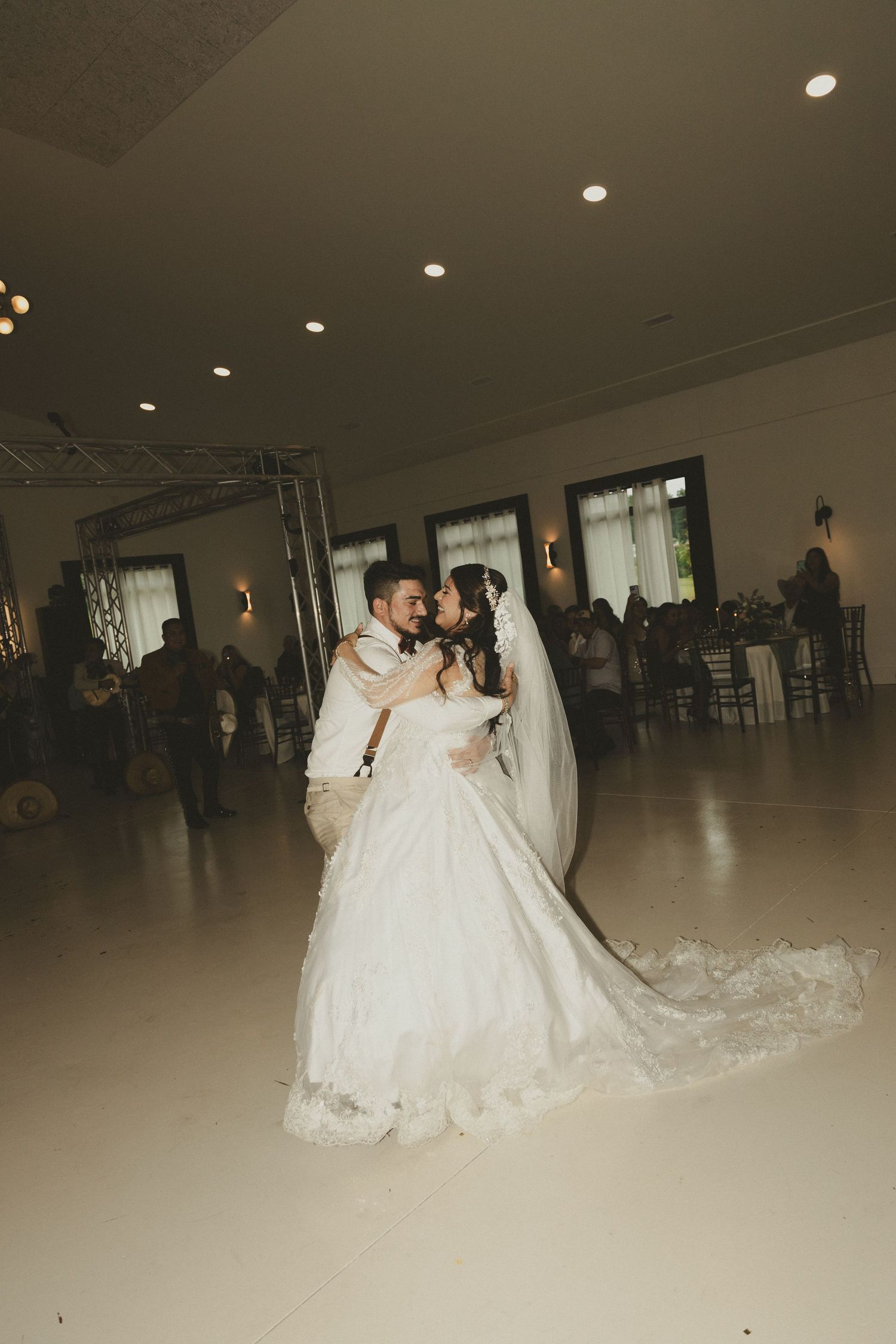 A romantic first dance moment between newlyweds in a beautifully lit reception hall during their wedding celebration.