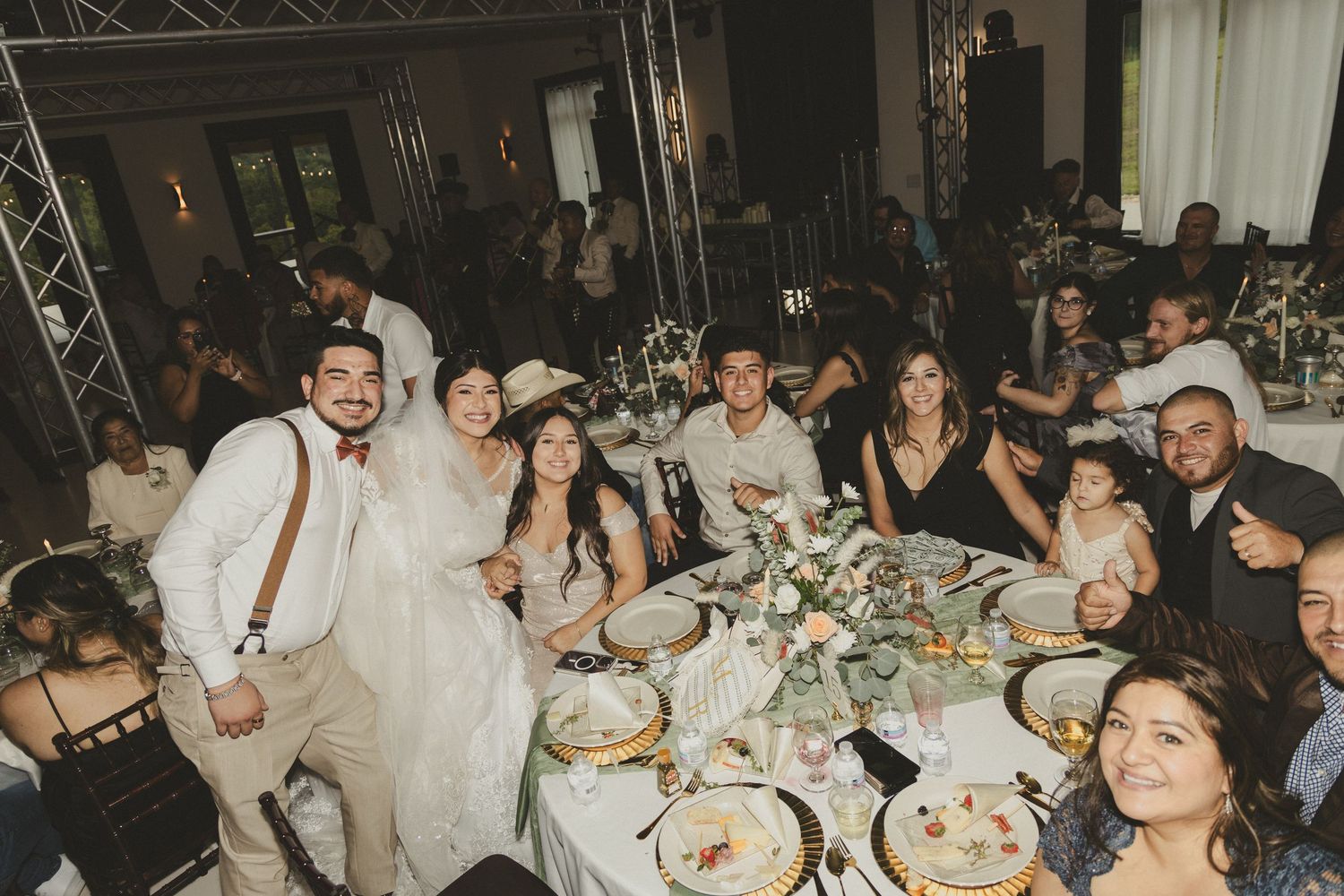 Guests enjoying a lively wedding reception dinner with tables filled with food and decor.