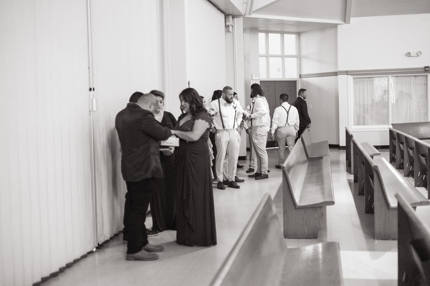 People standing in a bright white hallway looking at information posted on the walls during what appears to be an exhibition.