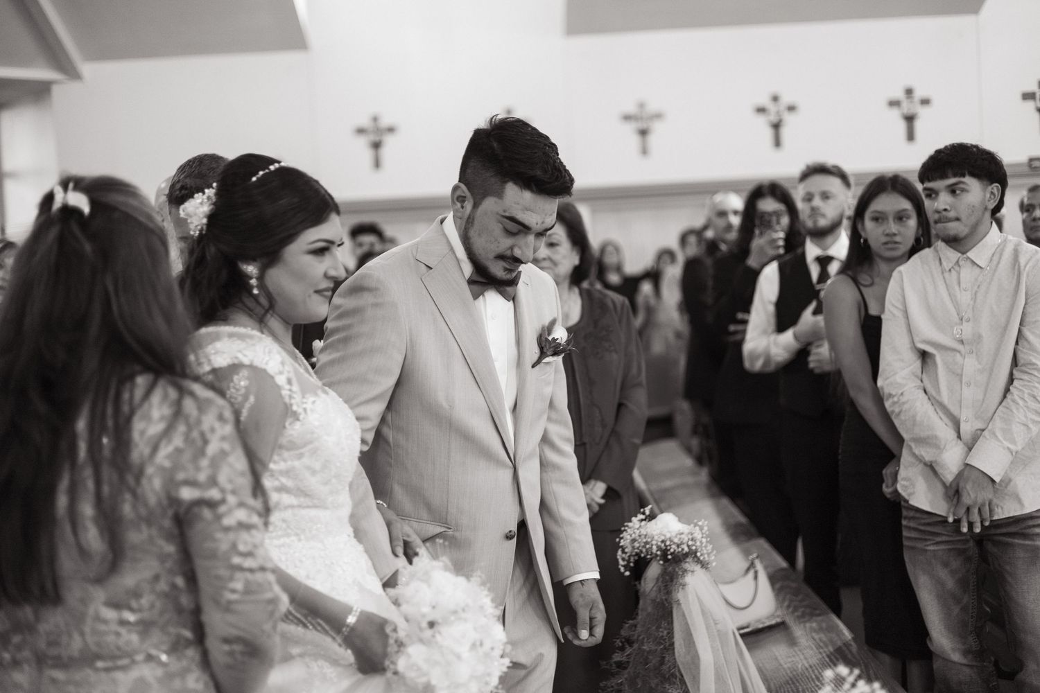 Black and white photo capturing an emotional moment during a wedding ceremony in a church with crosses on the walls.