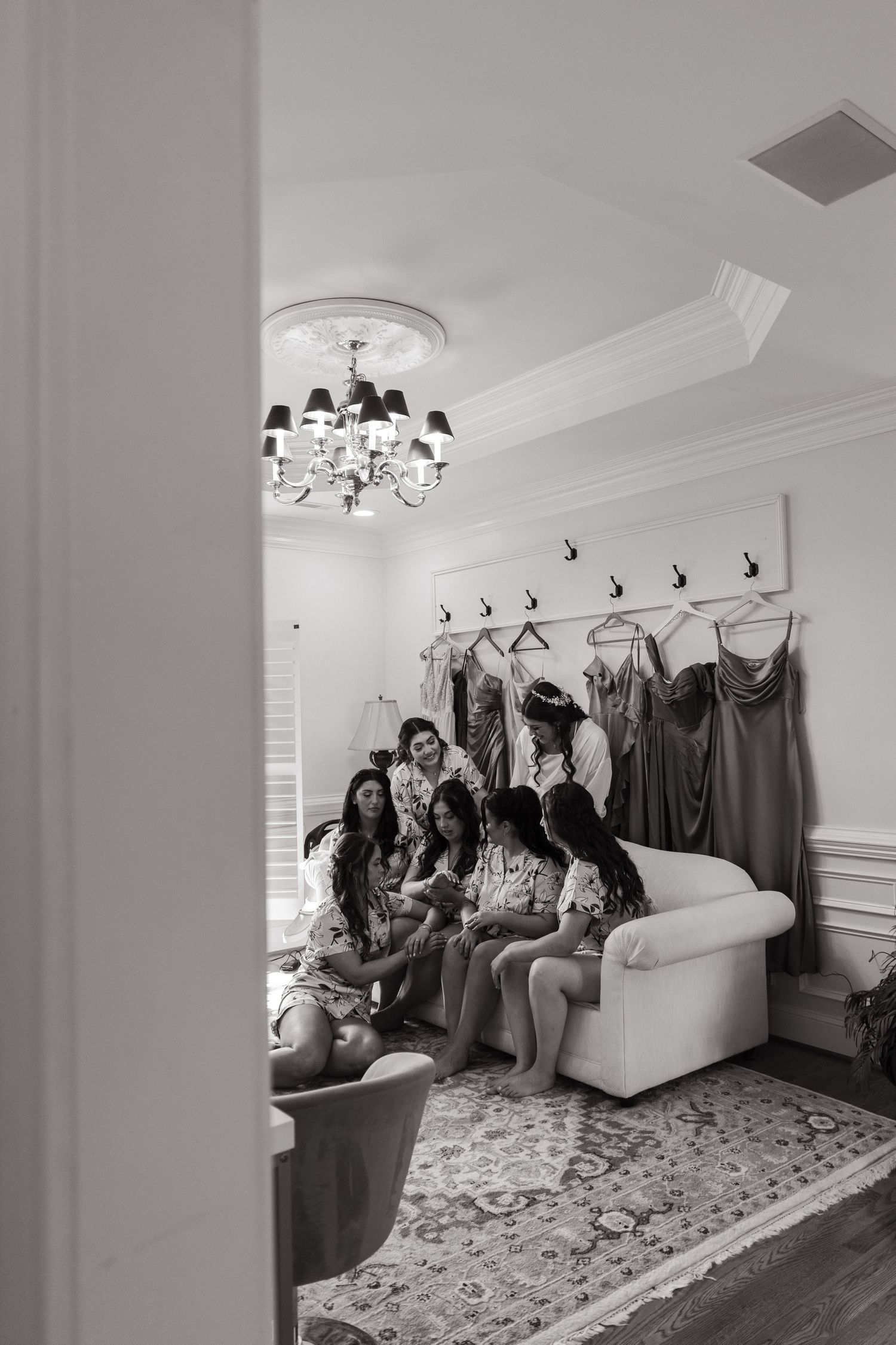 A group gathering in a bright white room with formal dresses displayed along the wall and elegant decor.